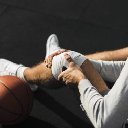 basketball-player-applying-bandage-knee basketball-player-applying-bandage-knee