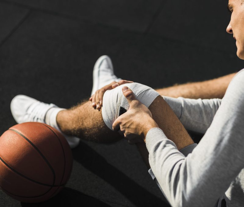 basketball-player-applying-bandage-knee